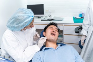 Oral surgeon examining a patient experiencing jaw pain, illustrating common TMJ disorder symptoms.