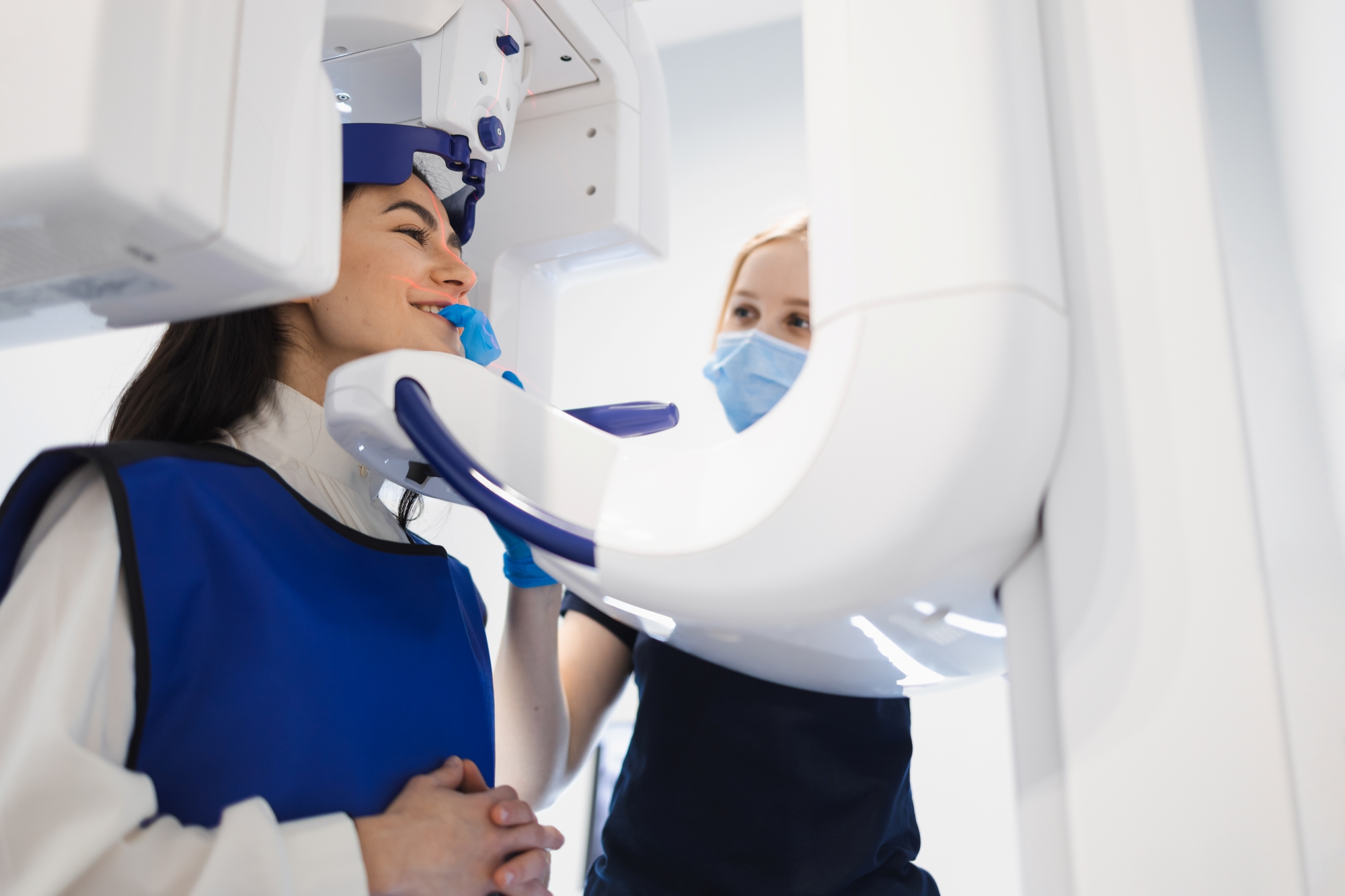 Female patient undergoes a dental computed tomography, and a radiologist makes a CT scan of the jaw.