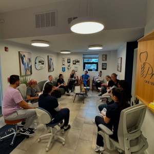 Premier Oral Surgery Group team meeting in a modern patient lounge, staff seated in a circle discussing care.