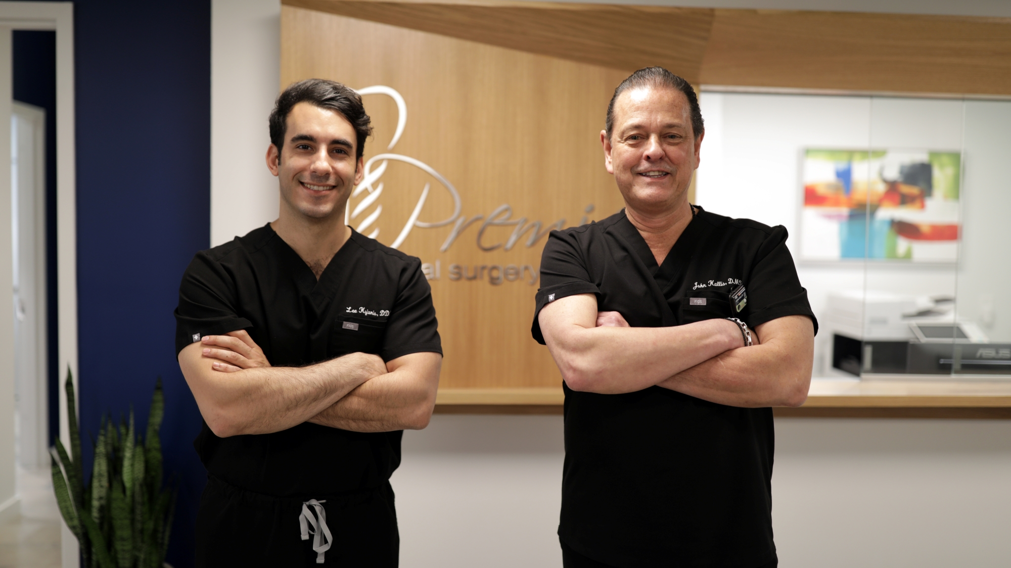 Two oral surgeons in black scrubs standing confidently at Premier Oral and Maxillofacial Surgery Group clinic.