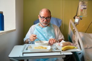 Hospital patient eating a soft meal during recovery, highlighting the importance of gentle nutrition after surgery.