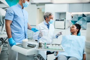 Dentist and oral surgeon reviewing X-rays and explaining treatment options to a patient in a modern dental clinic.
