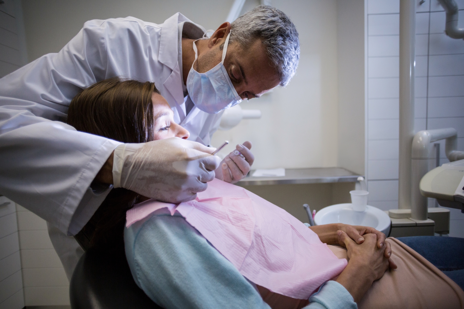 Oral surgeon examining a patient’s mouth during a clinical evaluation with careful attention in a treatment room.