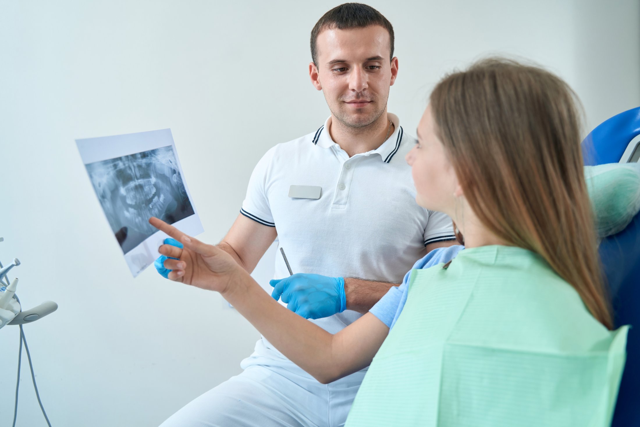 Dental professional explaining an X-ray to a seated patient during a consultation appointment.
