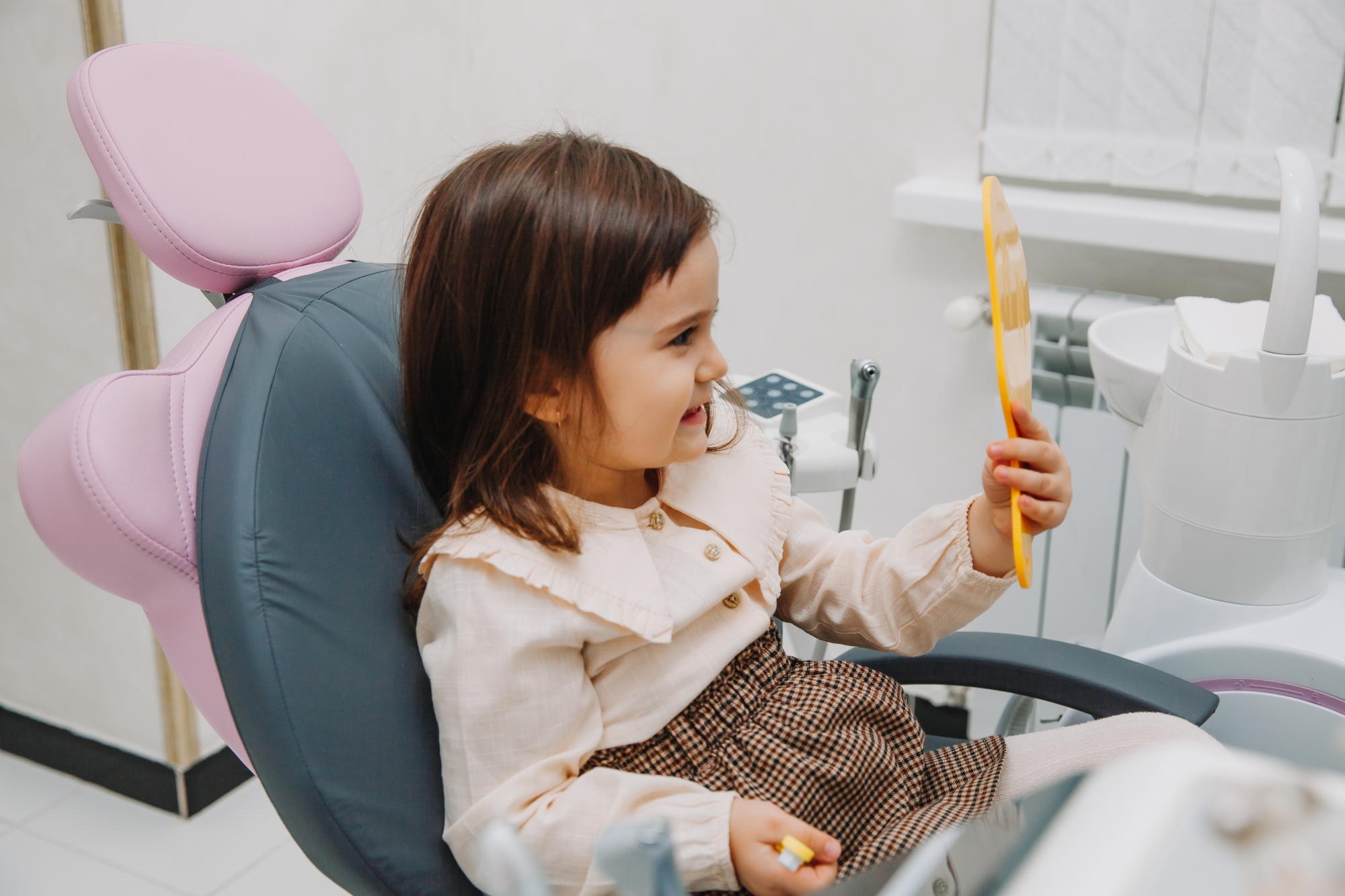 Smiling young girl at Premier Oral looking at herself in the mirror.