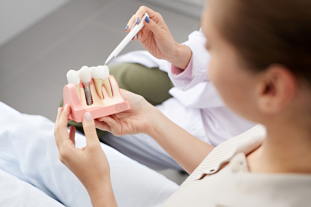 Dentist explaining a dental implant model to a patient during consultation at Premier Oral and Maxillofacial surgery group.