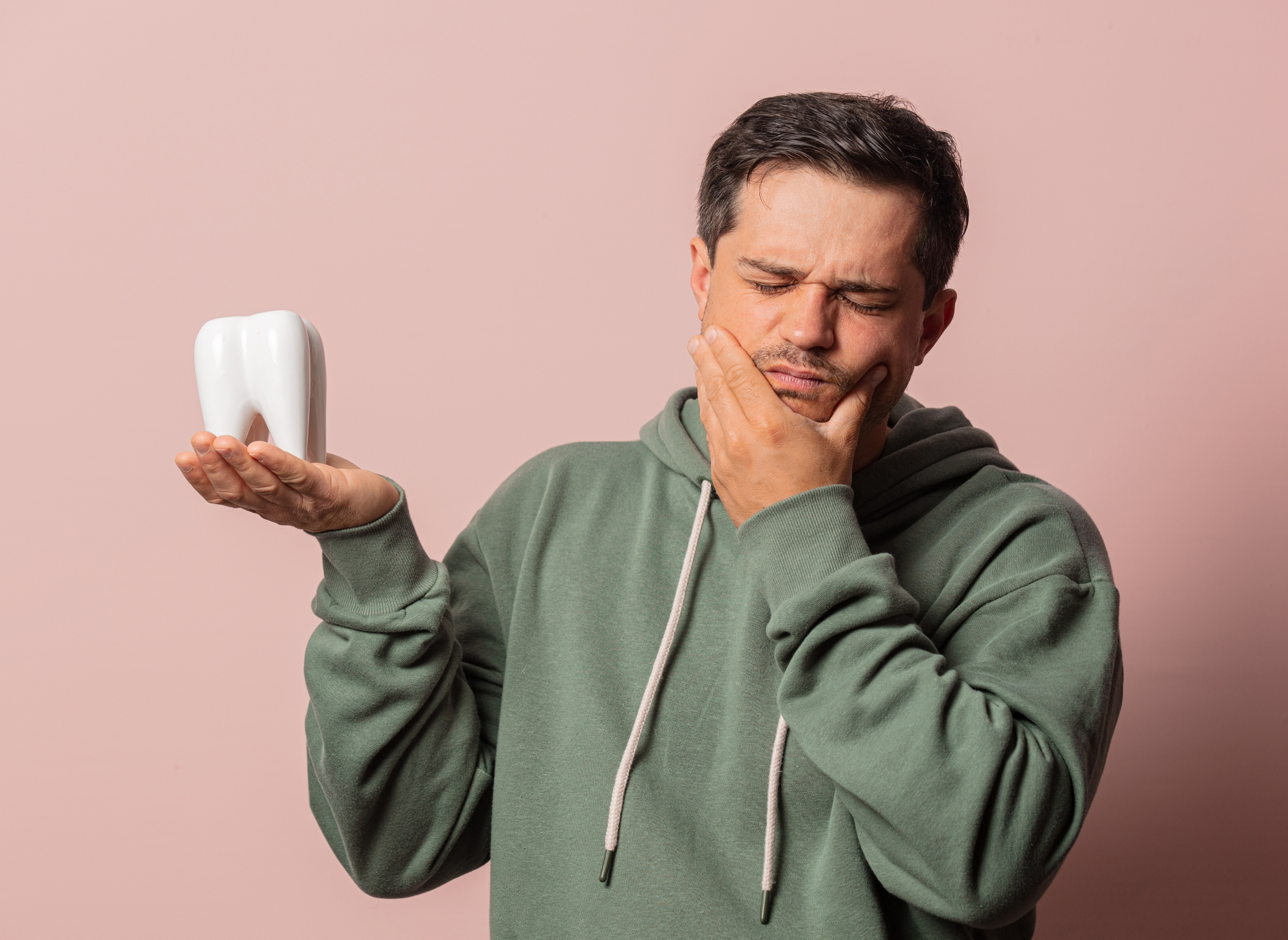man with a toothache holds a tooth in his hand.