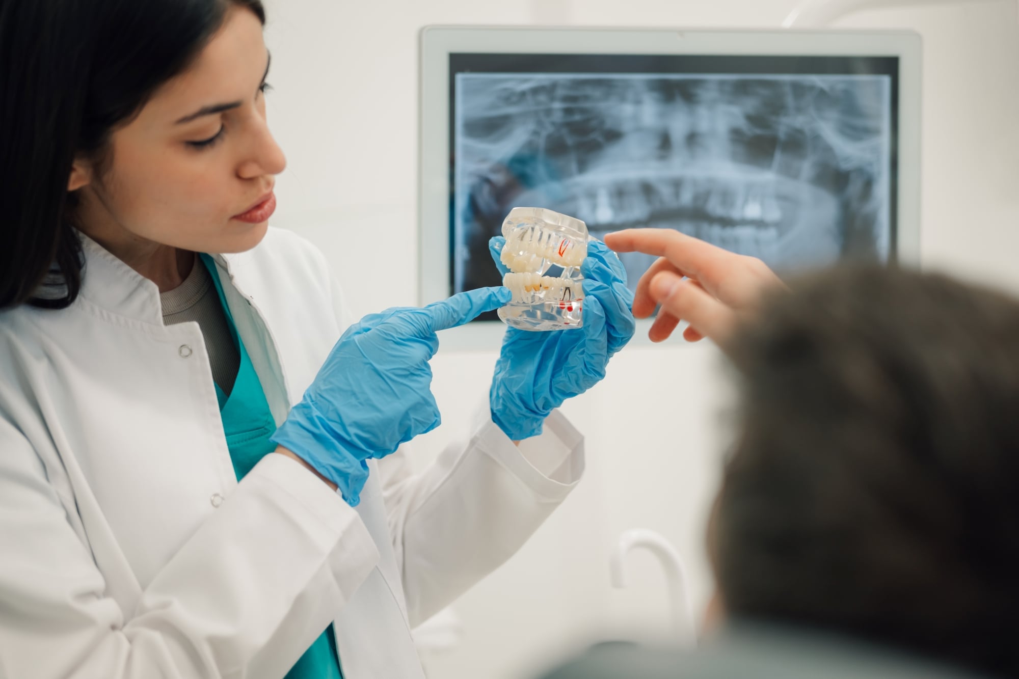 Oral surgeon holding dental implant model during patient consultation for implant treatment planning at Premier Oral.