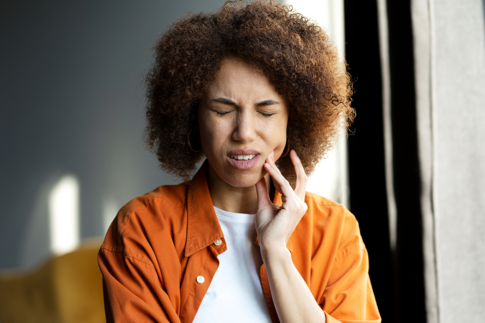 A woman experiencing the first symptoms of TMJ disorder.
