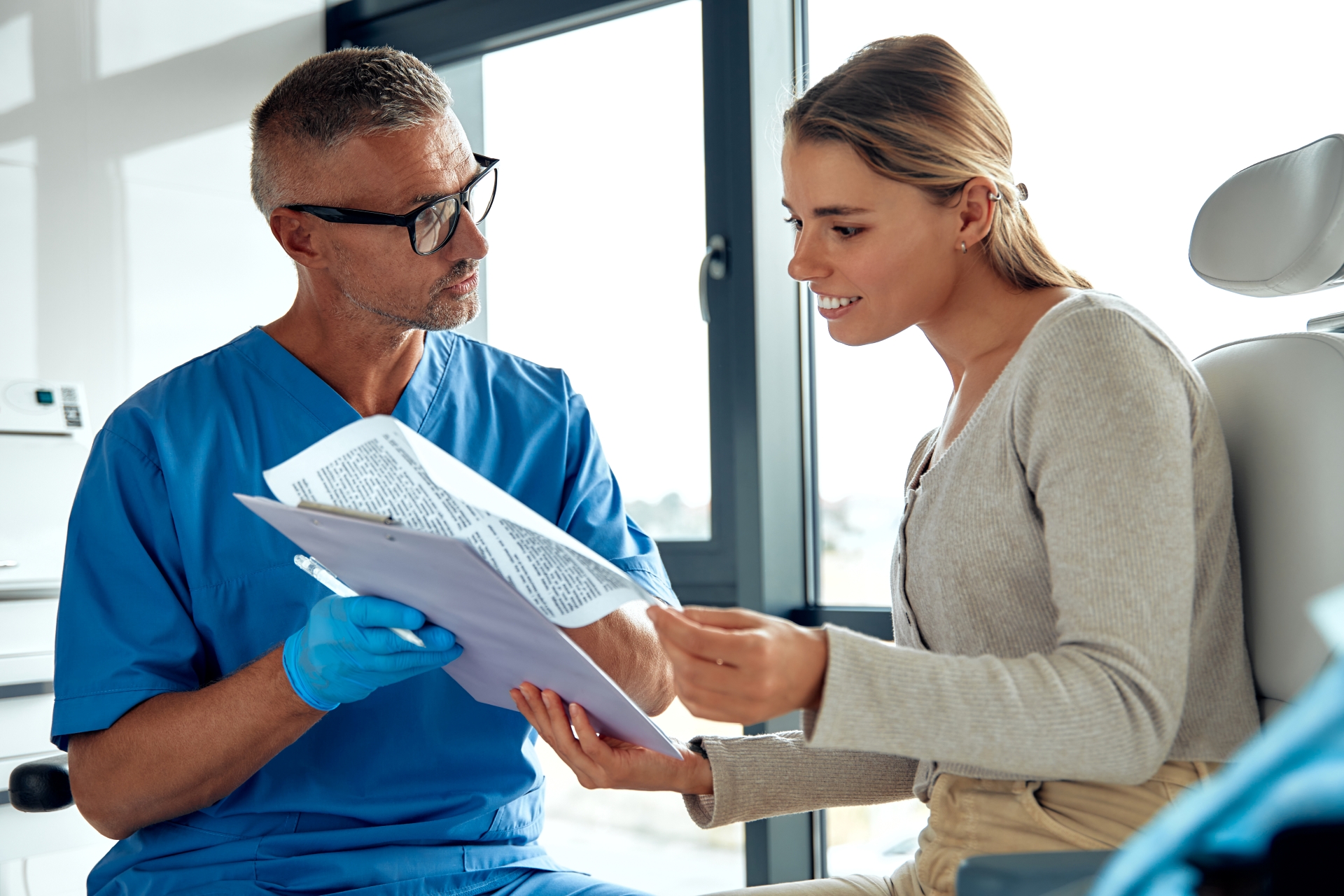 Oral surgeon discussing post-op recovery and diet instructions with patient after procedure at Premier Oral.
