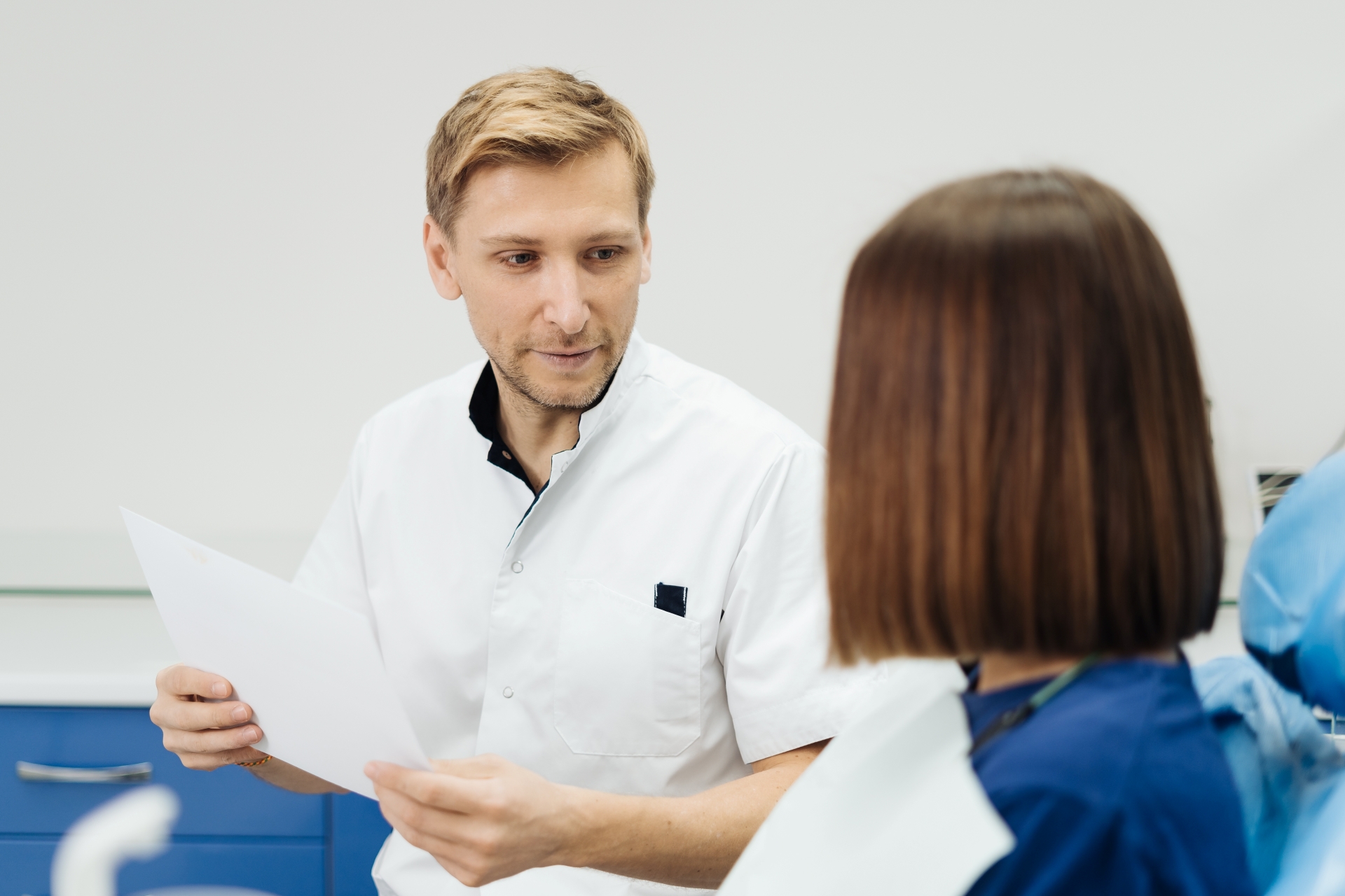 Oral surgeon discussing recovery progress and post-op care with patient during follow-up visit.