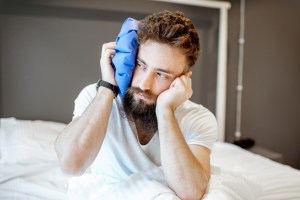 Patient resting with an ice pack on the jaw during facial surgery recovery at home.