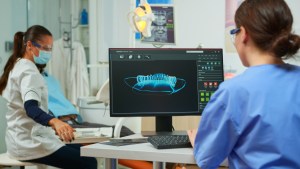 3D dental imaging displayed on monitor during treatment planning consultation with oral surgery team.