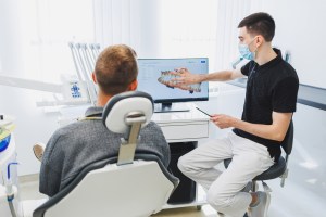 Dental professional explaining 3D dental imaging and treatment plan during patient consultation.