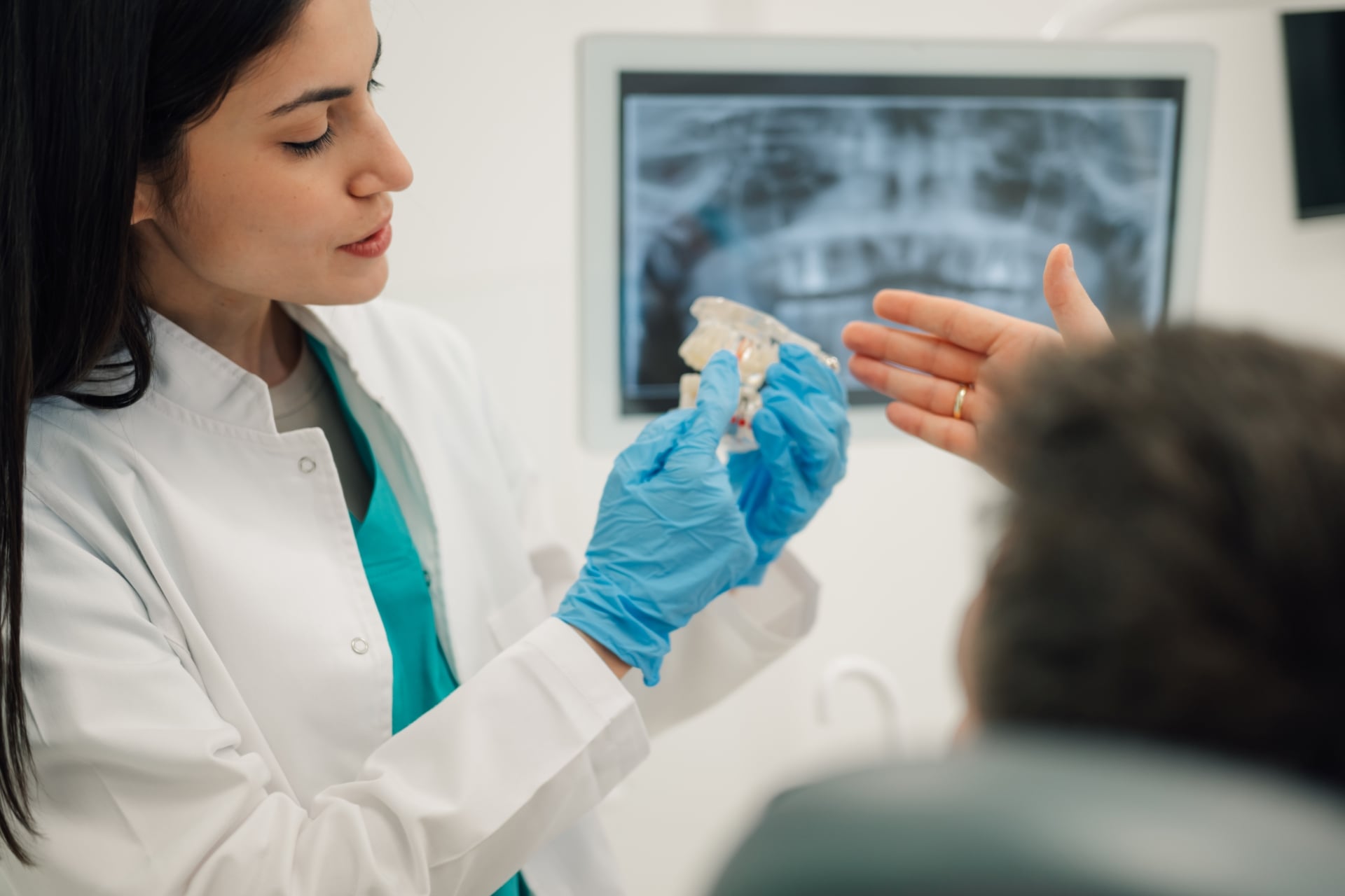 Oral surgeon explaining impacted canine treatment using a dental model during patient consultation.