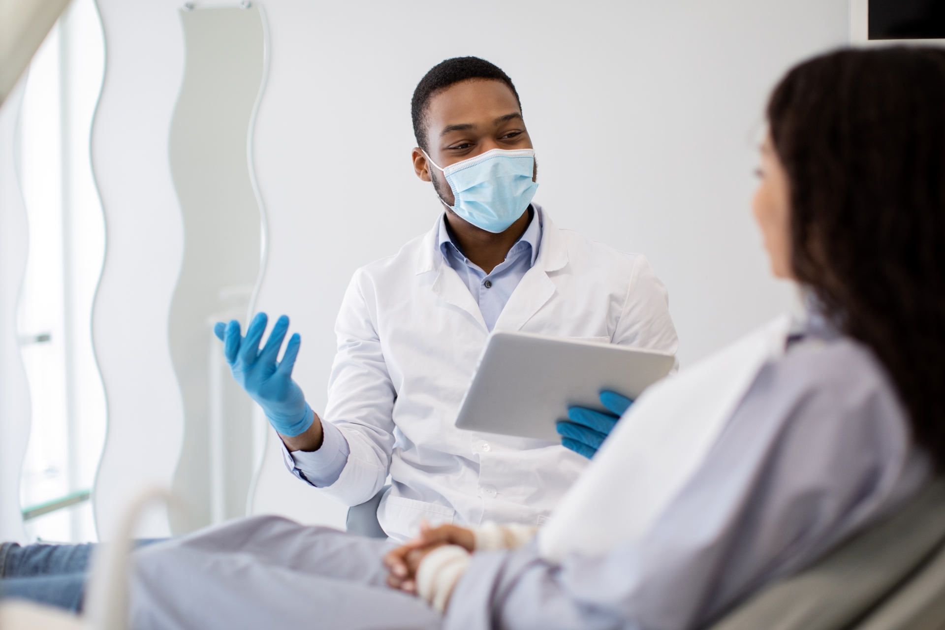 Oral surgeon discussing wisdom teeth treatment plan and recovery expectations with patient during consultation.