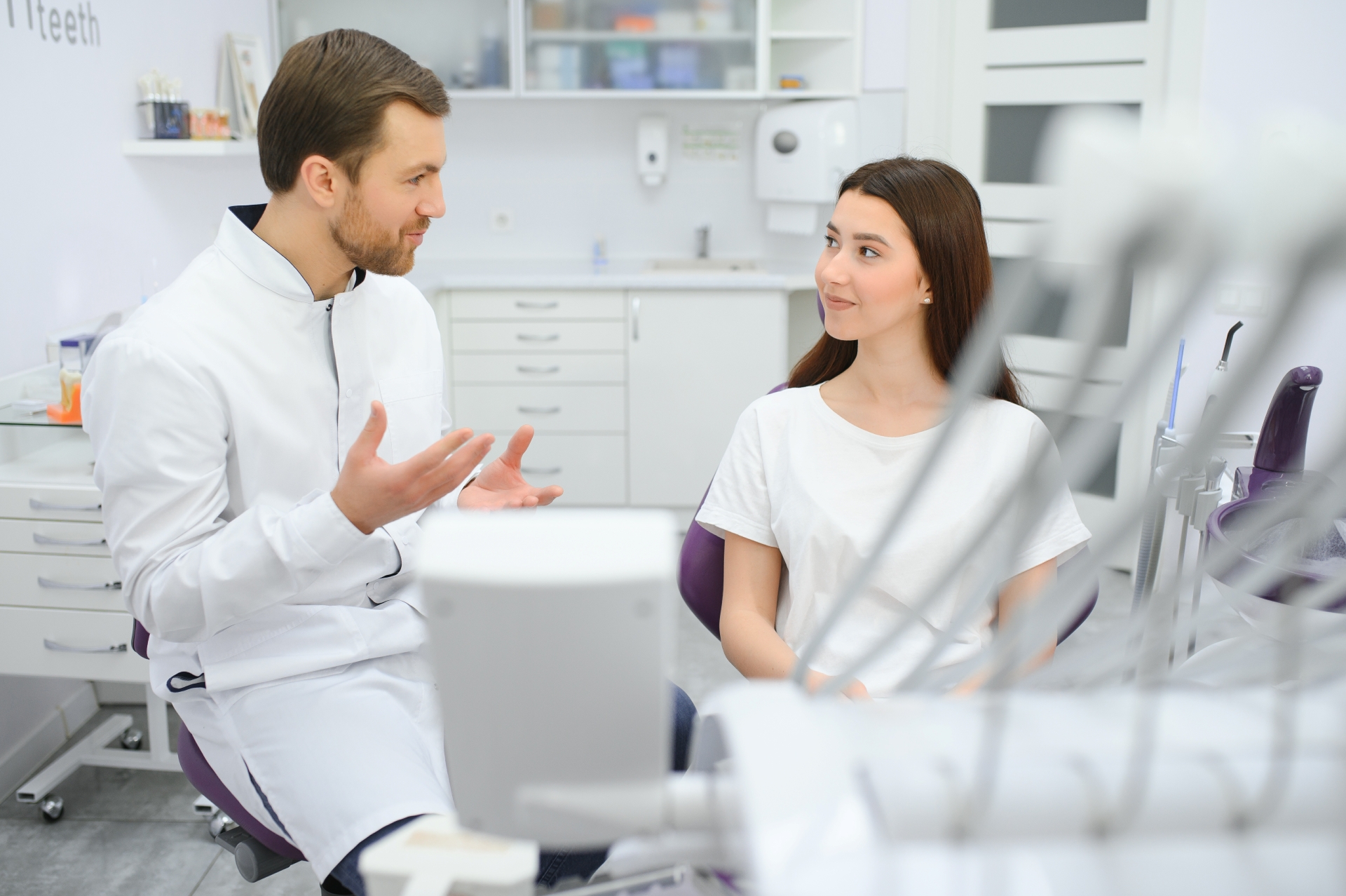 Doctor evaluating and discussing treatment plans with a female patient sitting in a clinical chair at Premier Oral and Maxillofacial Surgery Group.