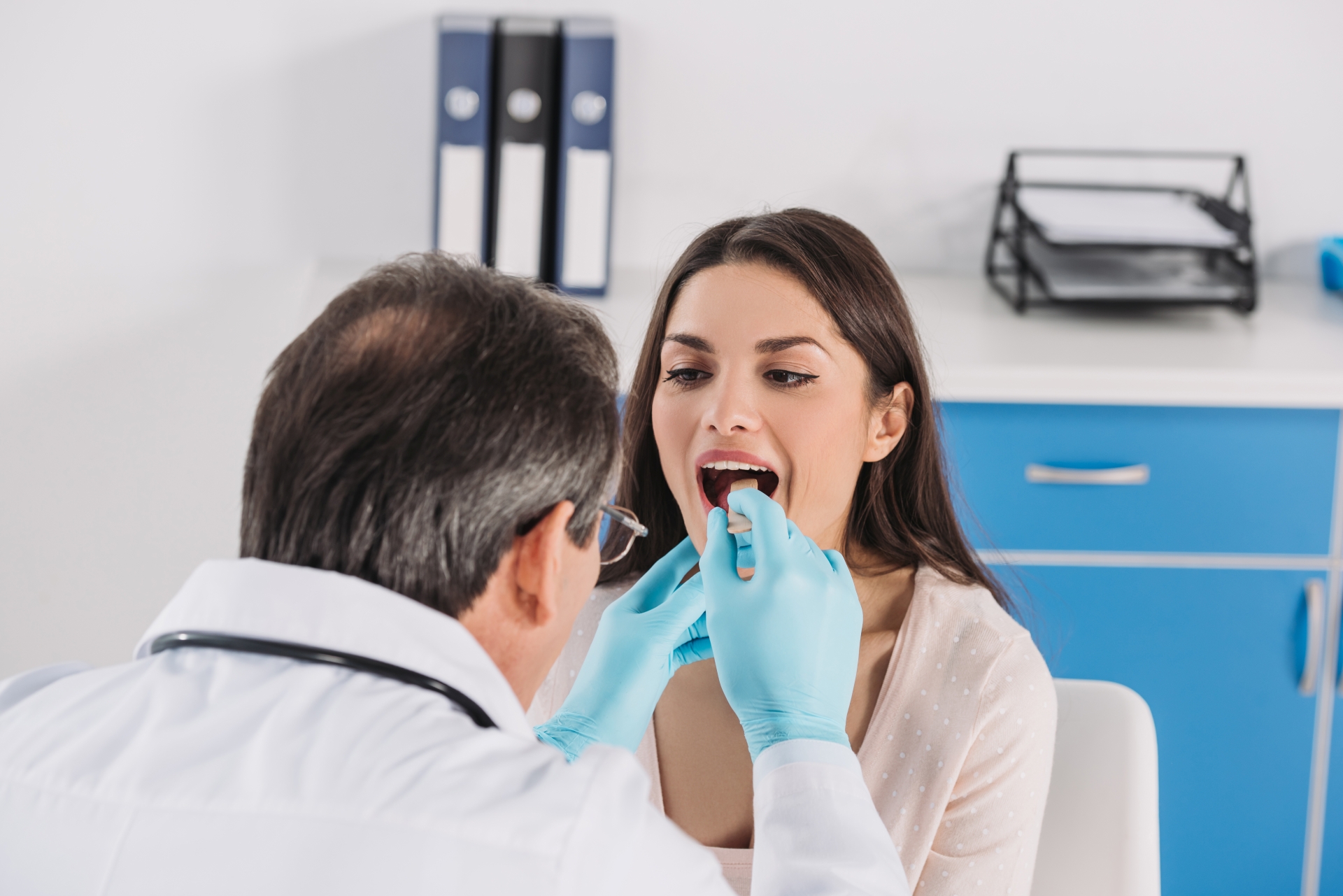 Premier Oral and Maxillofacial Surgery group doctor uses a small tool to perform an oral lesion exam on a patient.