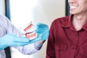 A doctor from Premier Oral shows a jaw model to a smiling patient during a consultation.