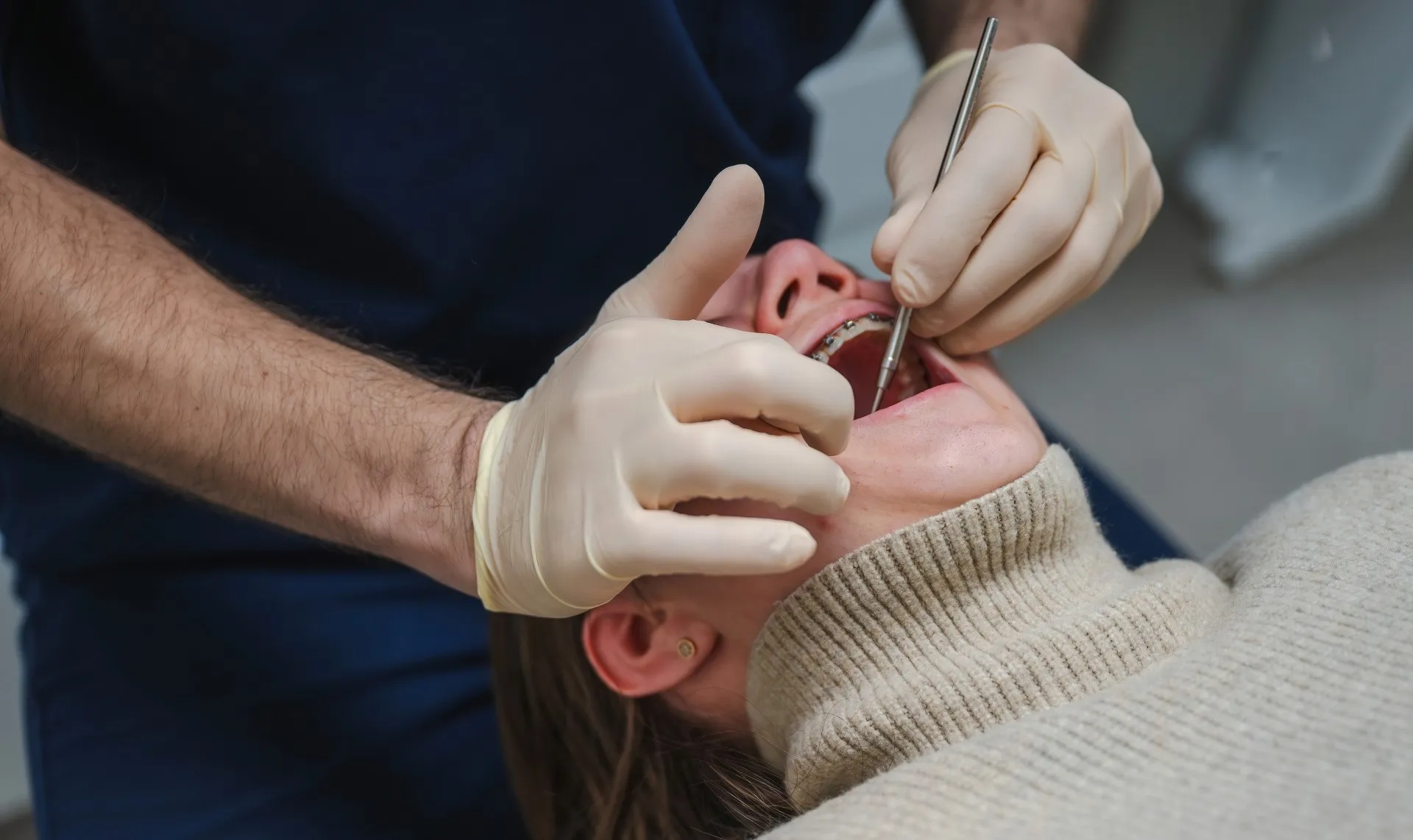 A Premier Oral surgeon carefully performs an oral examination on a patient.