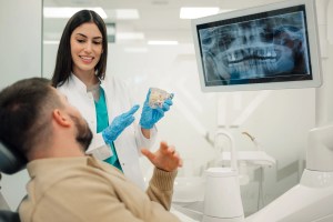 Premier Oral’s dentist showing a dental model and 3D imaging to a patient.
