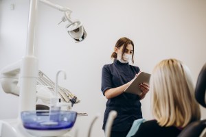 Premier Oral dentist speaks with a patient while reviewing and evaluating symptoms.