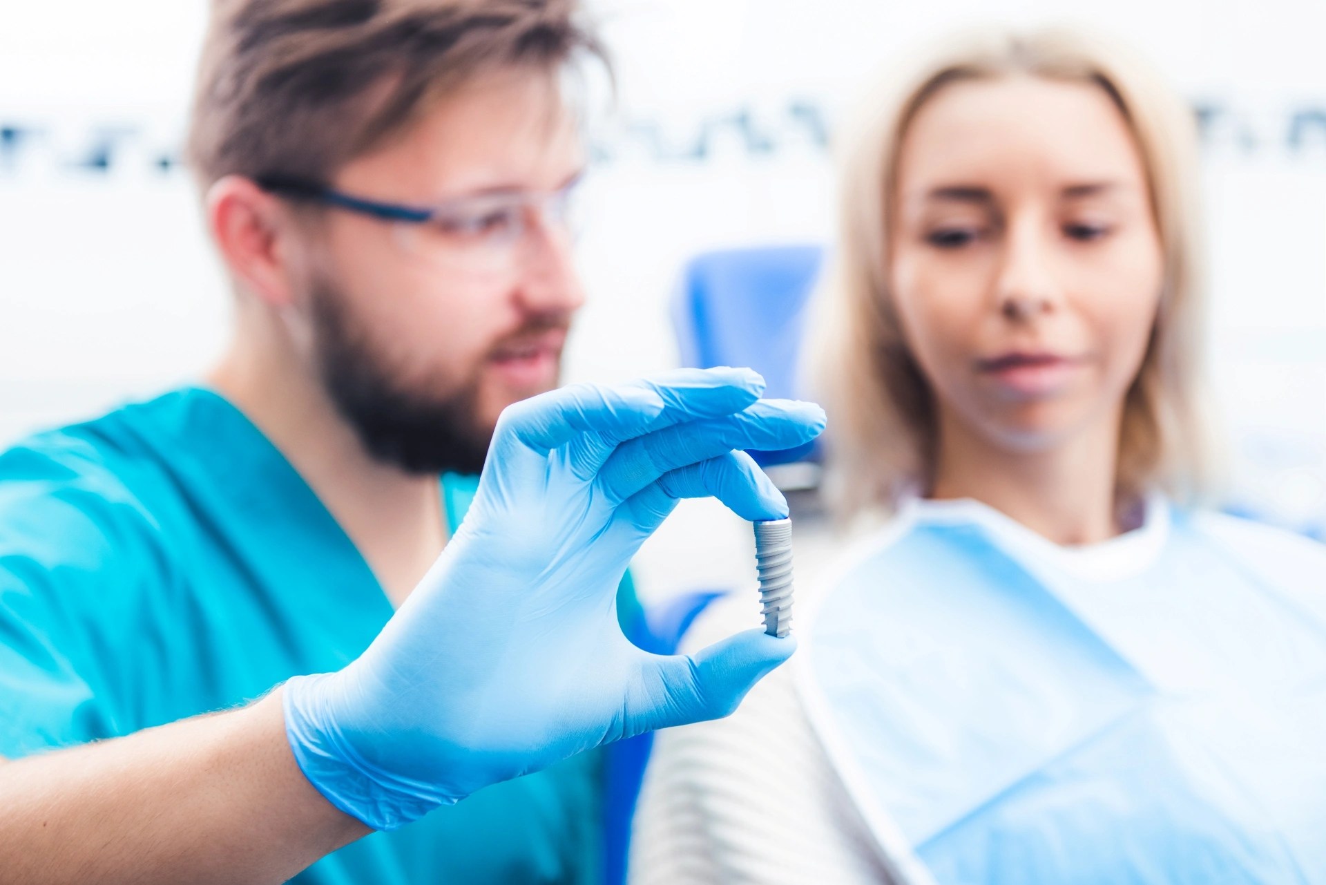 Premier Oral Surgery and Maxillofacial group’s surgeon showing a dental implant model to a female patient.