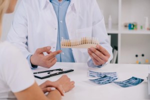 Dentist at Premier Oral pointing to a dental model during a consultation.