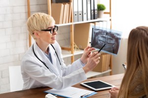 A Premier Oral surgeon shows a dental scan to a patient during an extraction consultation.