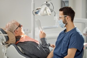 Older patient discussing dental implant options with an oral surgeon.