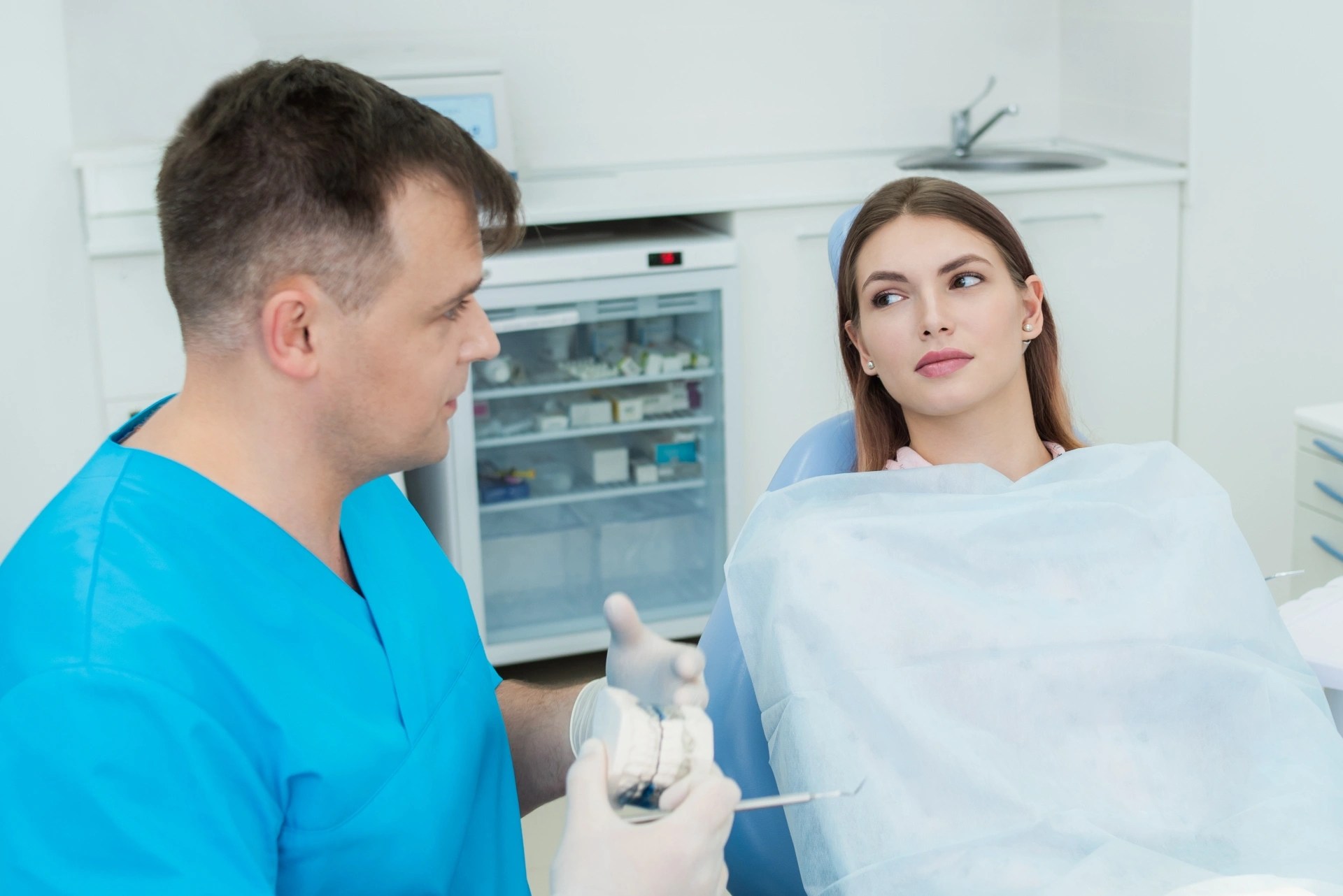 Premier Oral doctor explaining anesthesia plans to a female patient before dental extraction.