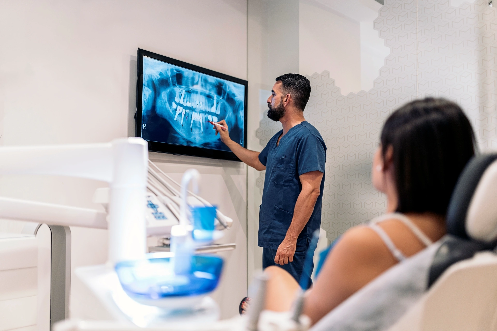 Premier Oral specialist reviews a panoramic dental X-ray with a patient in a clinic.