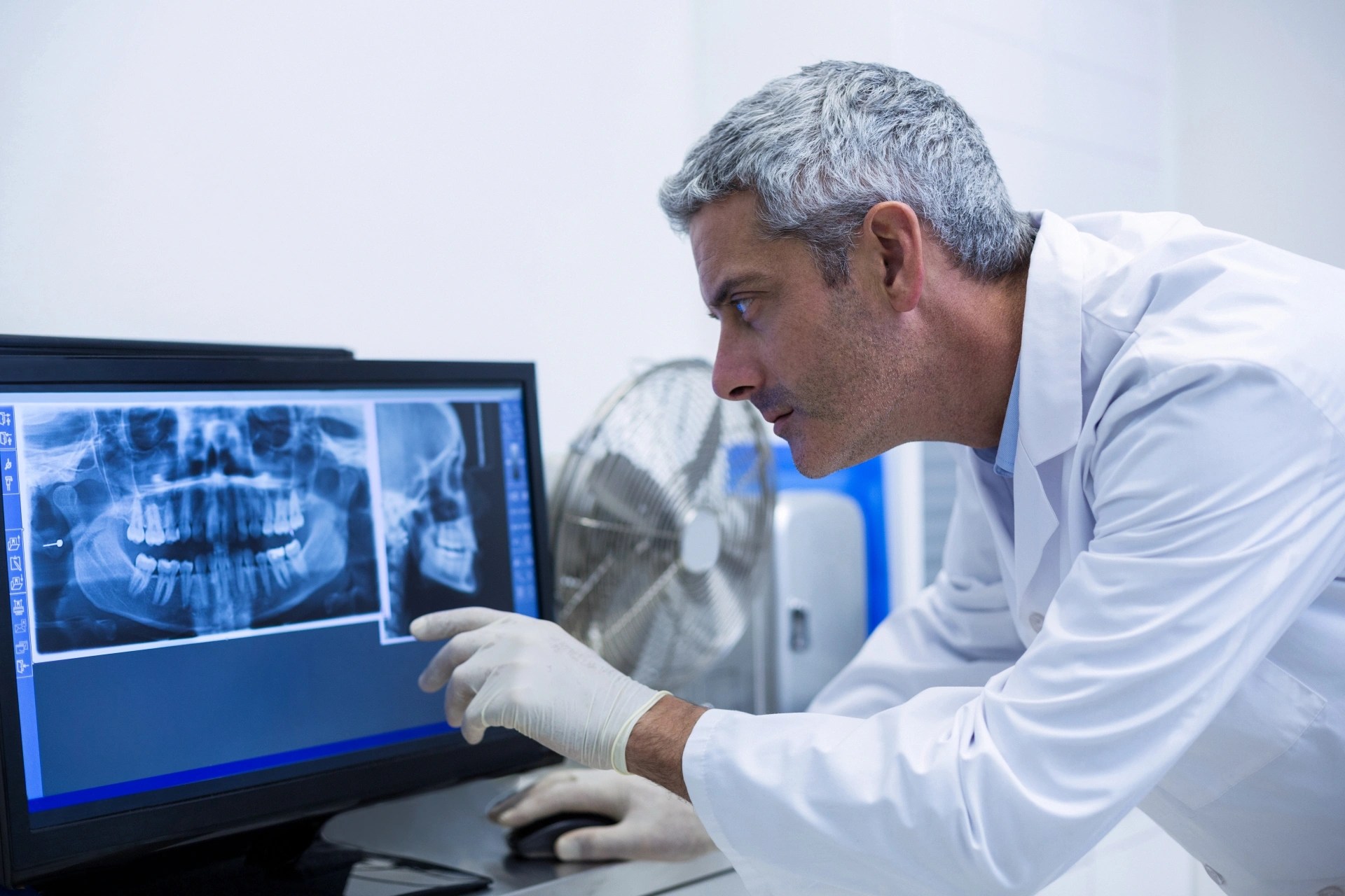 Oral surgeon reviewing dental imaging to assess implant candidacy. 