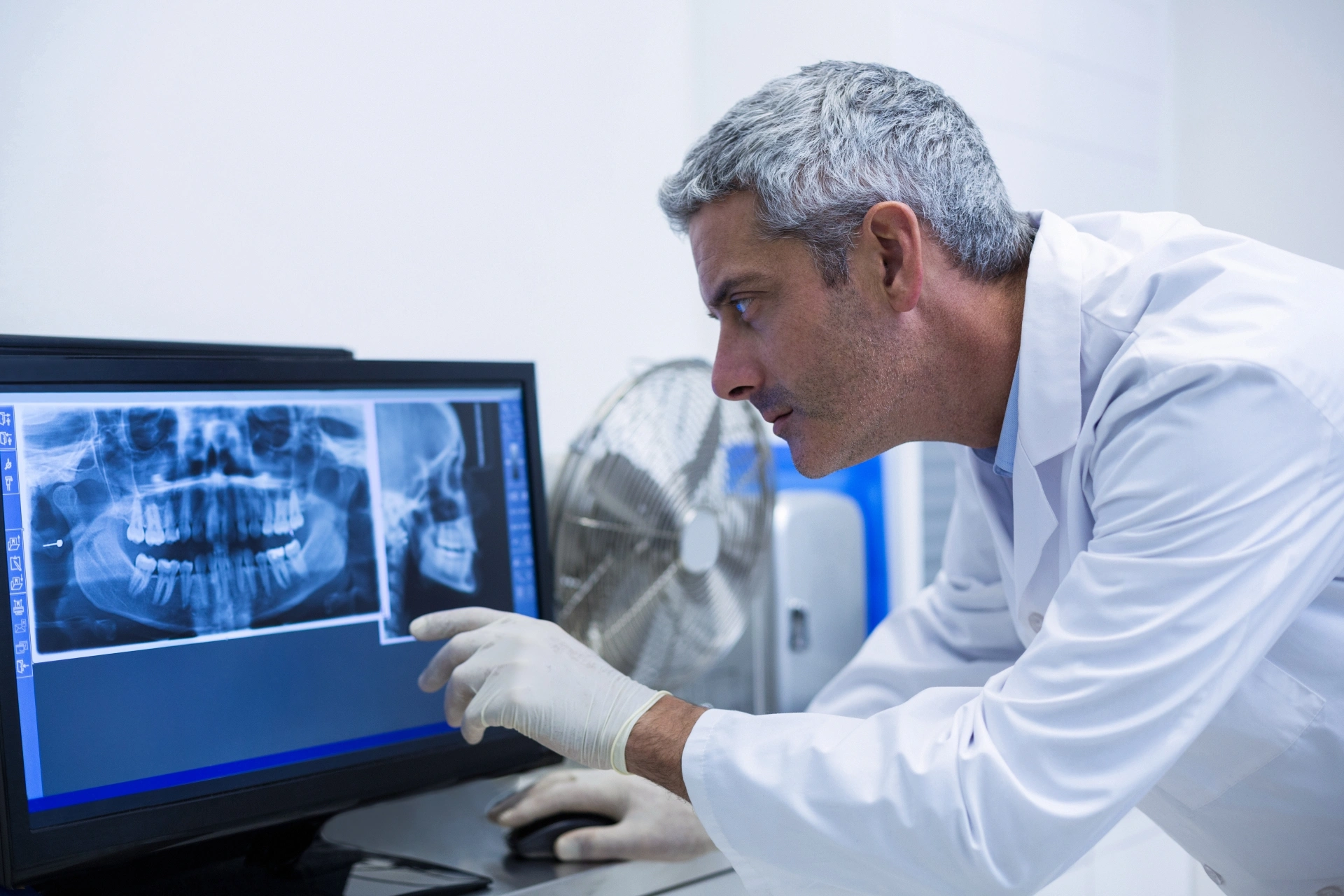 Oral surgeon reviewing a dental X-ray to assess a patient’s teeth and jawbone.