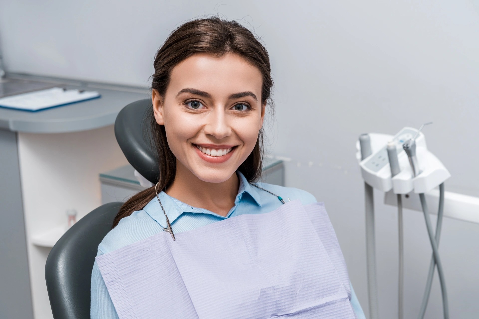 Smiling woman in a dental chair during a consultation about implant-supported overdentures and traditional dentures.