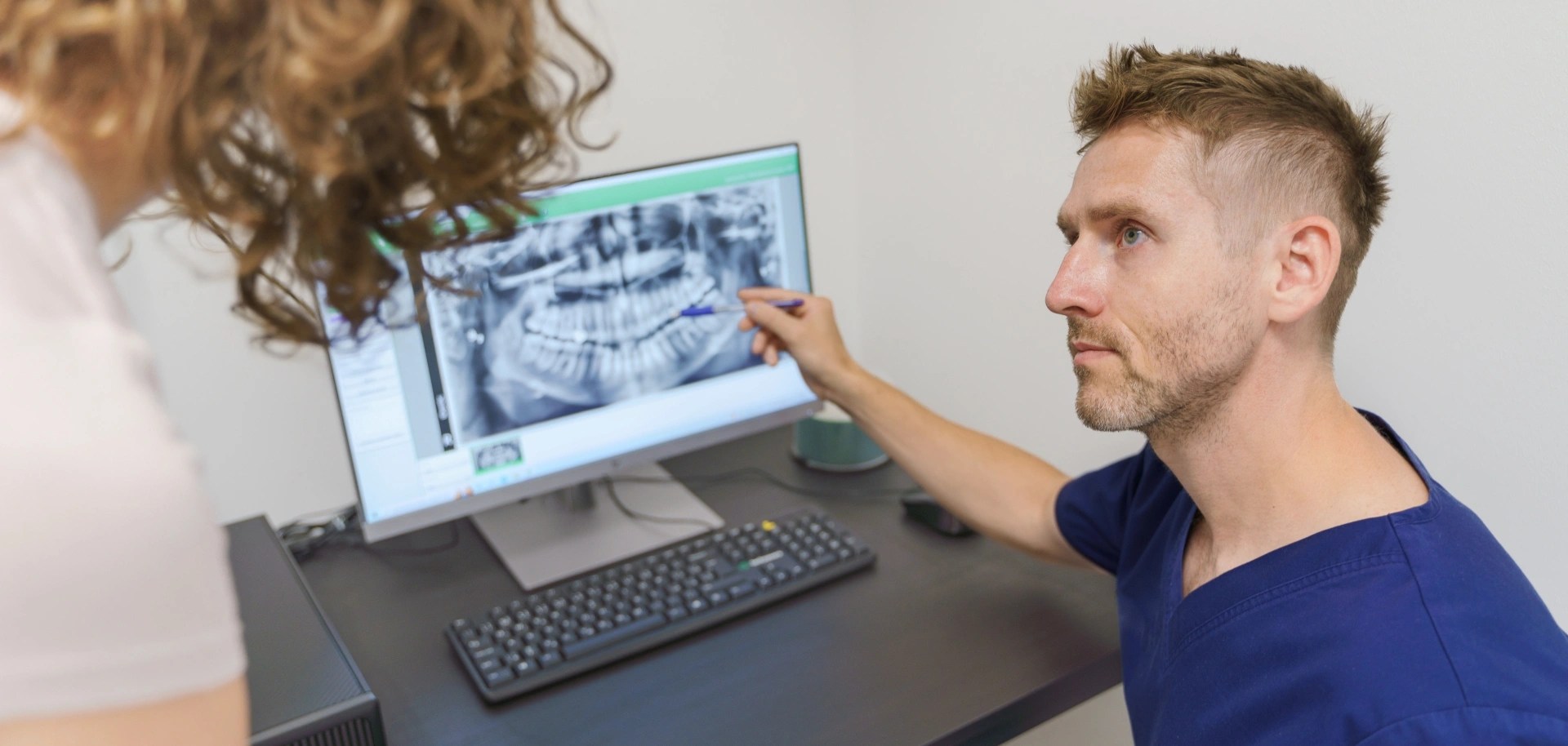 Oral surgeon reviewing 3D dental imaging before evaluating an implant.
